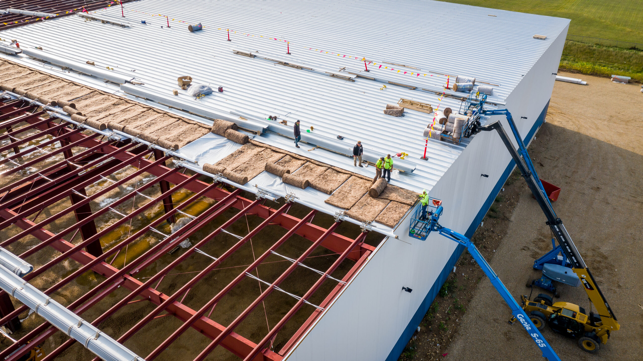 Construction workers installing roof panels on a warehouse - Super Roofing Pros